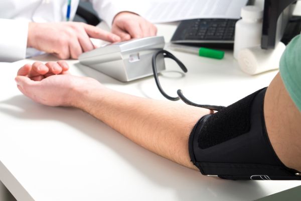 A Doctor taking blood pressure to the patient.