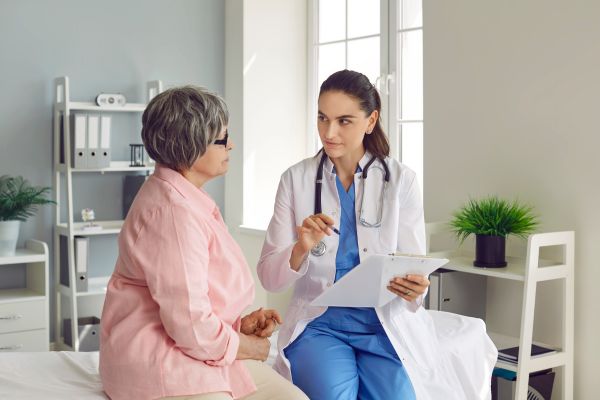 A woman conversing with a female doctor while discussing a medical chart.



