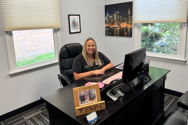 A female nurse practitioner is seated in her office.


